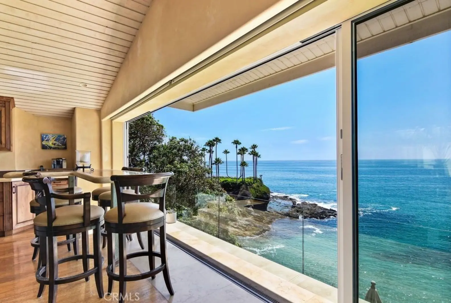 Breakfast nook with bar seating and sliding glass walls overlooking the coastline