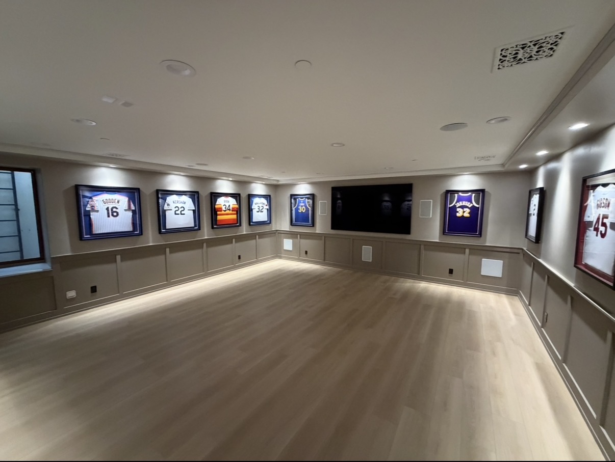 Completed home theater with framed jersey display, wall paneling and wood floor